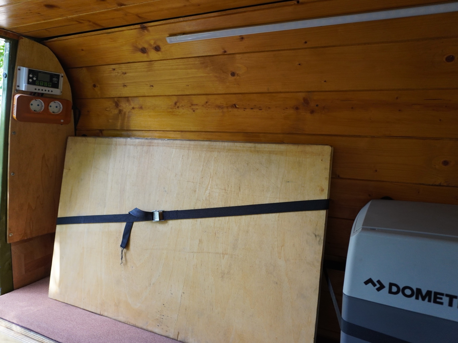 Wood-lined rear camper interior with solar controller